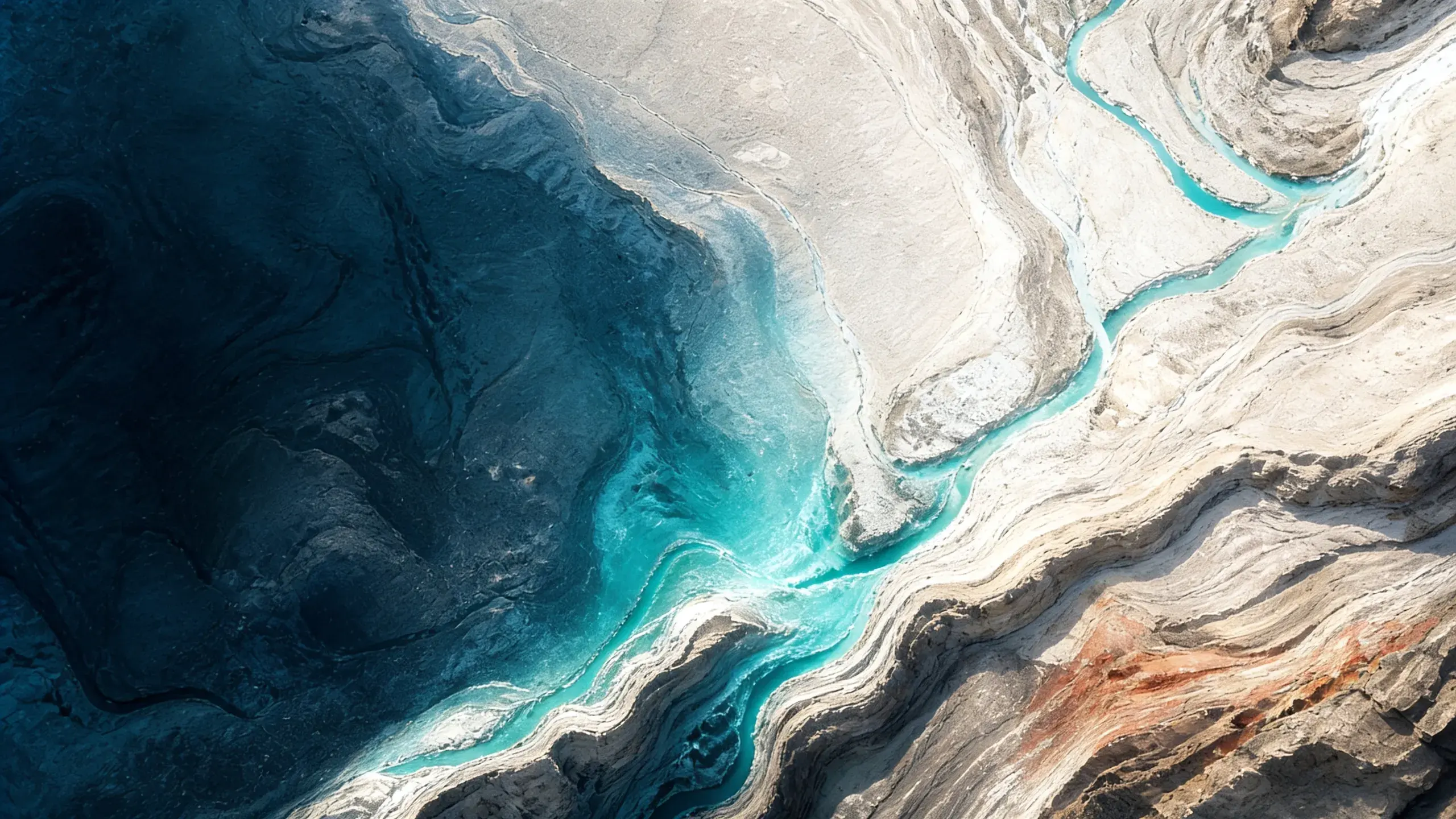 A wide view from above over a mineral canyon with a turquoise river